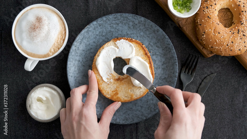 Fotografi Spreading cream cheese on bagel