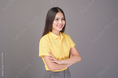 young confident beautiful woman wearing yellow shirt is on grey background studio