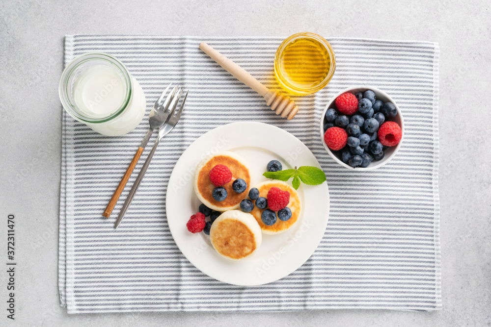 Food frame of assorted russian breakfast on white wooden table with copy  space. Pancakes (blini) with caviar, cottage cheese, honey, cereal, boiled  egg, coffee and milk. Stock Photo