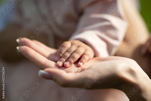 child's hand rests on mother's palm, selective focus