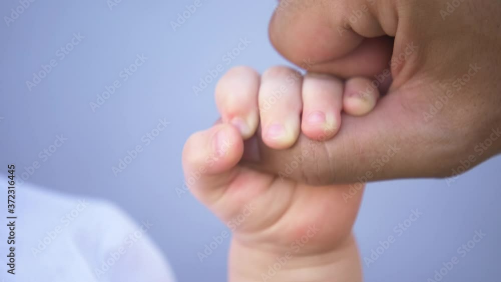 A kid hand holds the father's finger. Raising children in the family, taking care of children. Close-up of a kid's hand. Concept of family planning. A newborn child holds his father's hand. A kid hand holds the father's finger. Raising children in the family, taking care of children. Close-up of a kid's hand. Concept of family planning. A newborn child holds his father's hand.