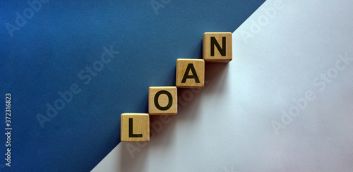 Wood block with word 'loan' stacking as step stair on paper blue and white background, copy space. Business concept success process.
