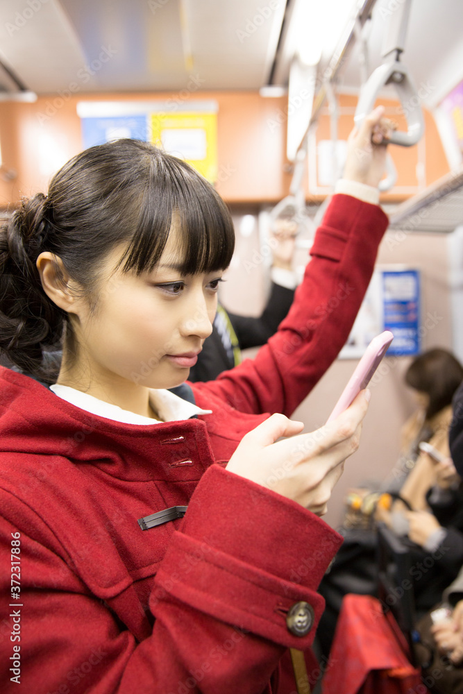 電車でスマホを見る女性 電車でスマホを見る女性
