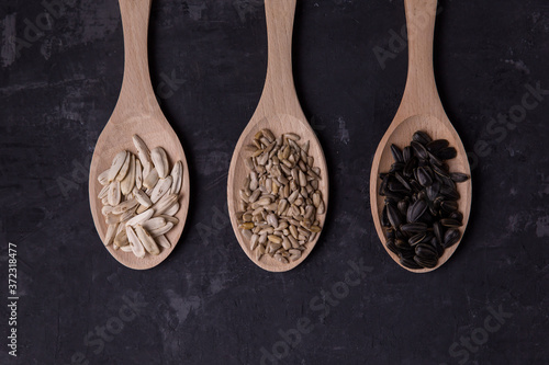 Sunflower seeds are black and white. mockup on three spoons top view on dark background 