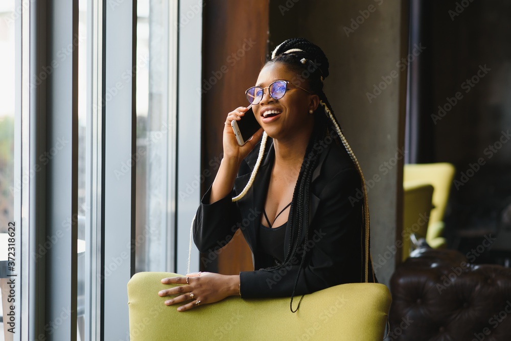 Fototapeta premium smiling black woman talking on the phone while resting in a cafeteria, selective focus