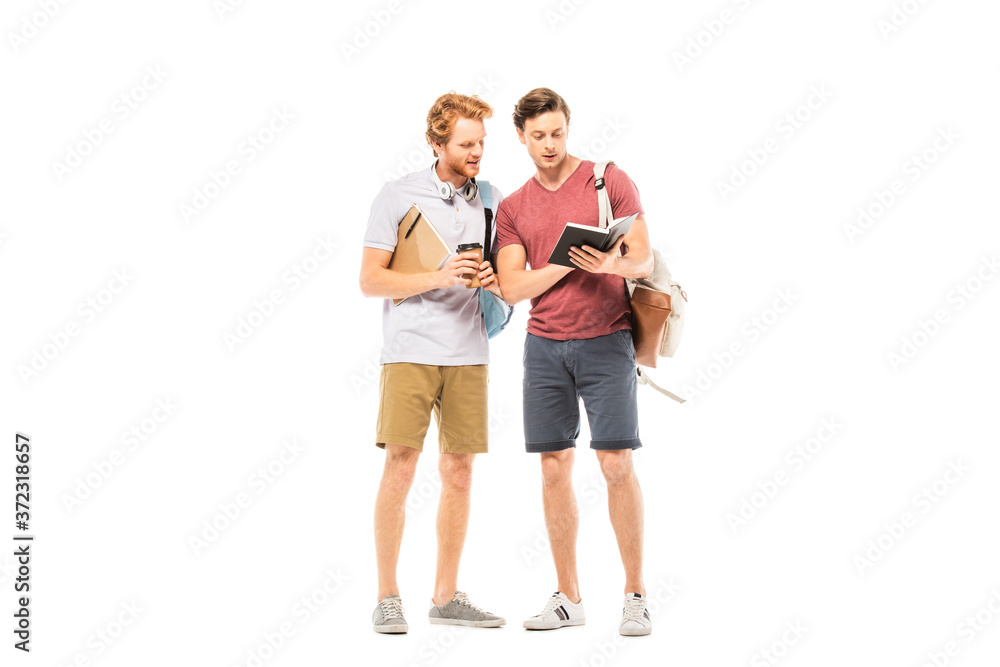 Students with coffee to go and backpacks looking at notebook isolated on white Students with coffee to go and backpacks looking at notebook isolated on white