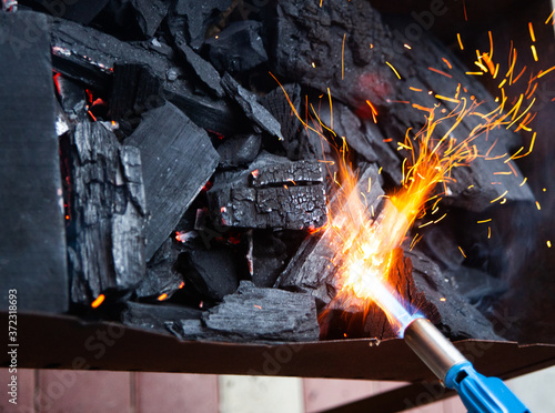 Igniting coal with a gas burner. Preparation of coals for barbecue