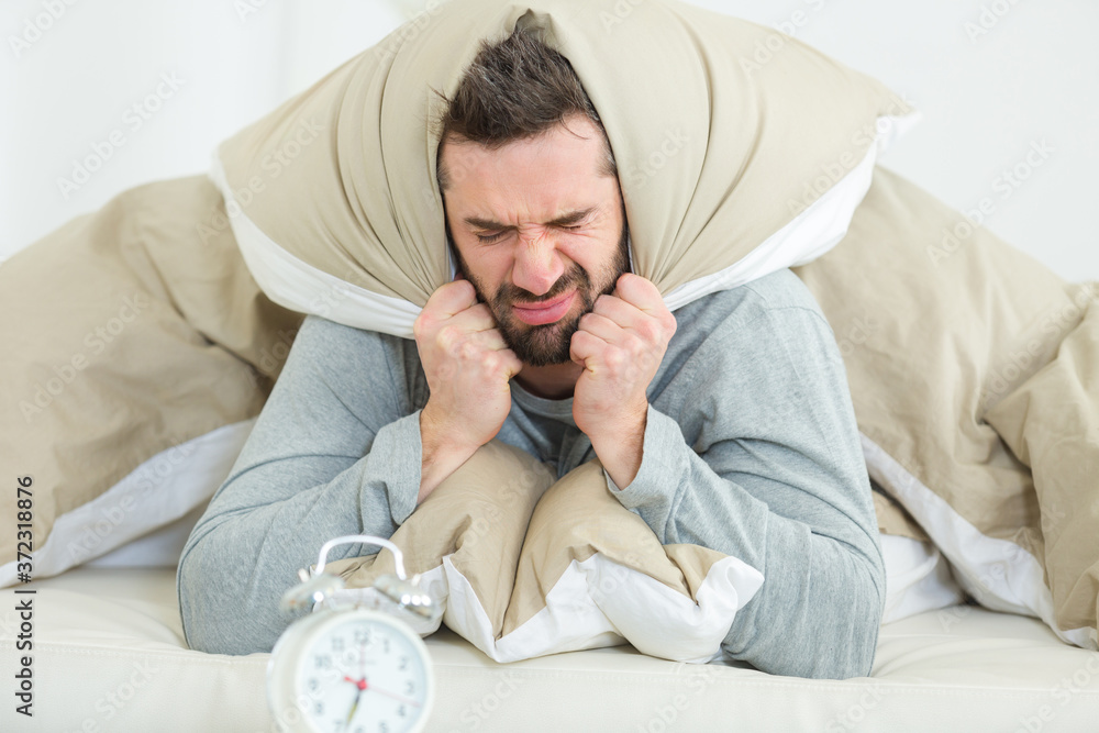 young man in bed angry about waking up young man in bed angry about waking up
