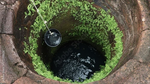 A pulling a bucket of water from an ancient well.