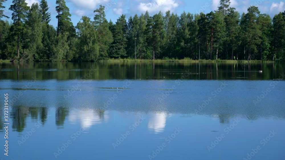 A small lake with two runners in the background and forest behind them. No camera movements, filmed in realtime at 4K. A small lake with two runners in the background and forest behind them. No camera movements, filmed in realtime at 4K.