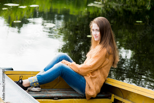 Beautiful young woman in a yellow knitted sweater and jeans posing in nature
