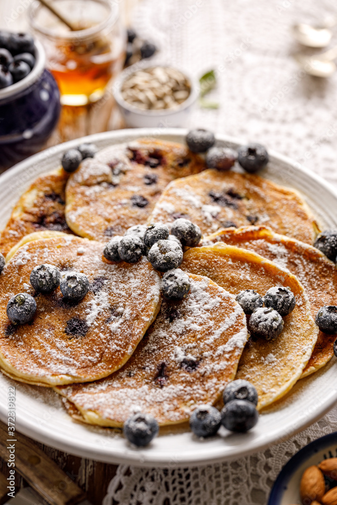 Pancakes with blueberries sprinkled with powdered sugar close up view