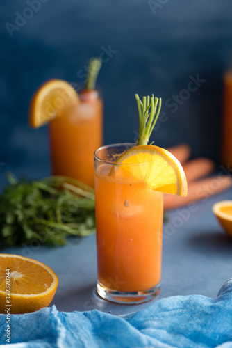 Fresh orange and carrot juice on blue background.