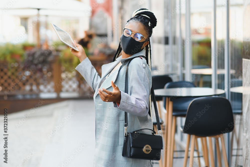 African american young volunteer woman wearing face mask outdoors. Coronavirus quarantine and global pandemic.