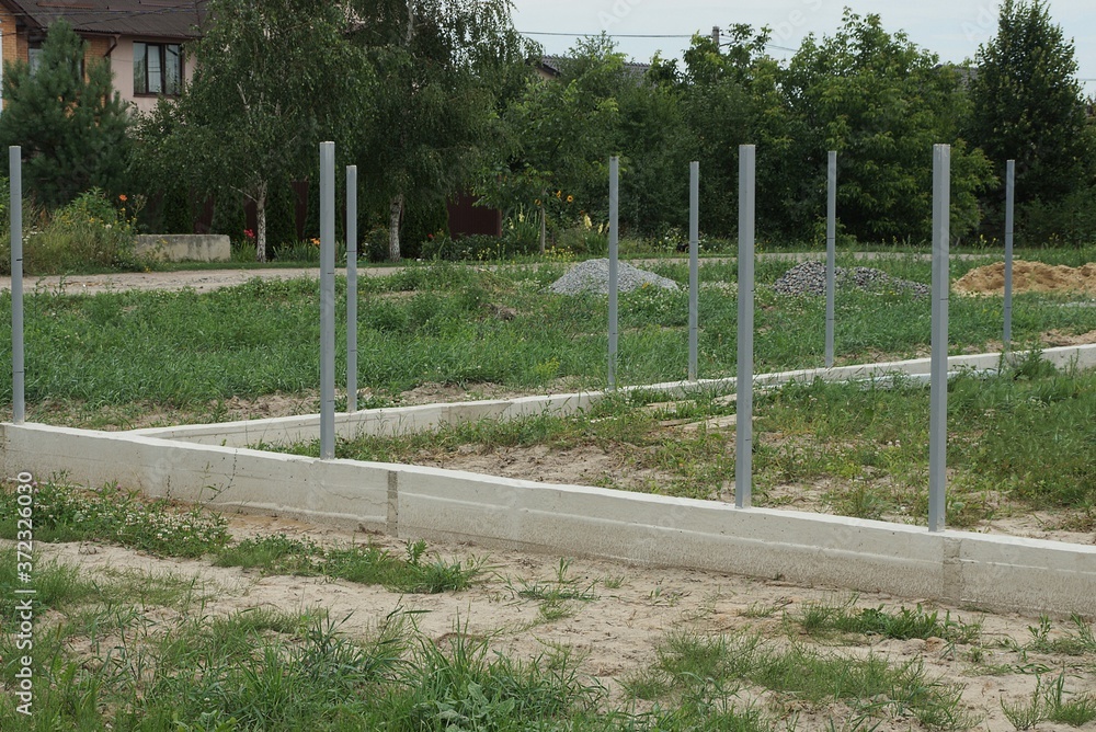 gray concrete foundation with iron pillars outdoors on a construction site in green grass