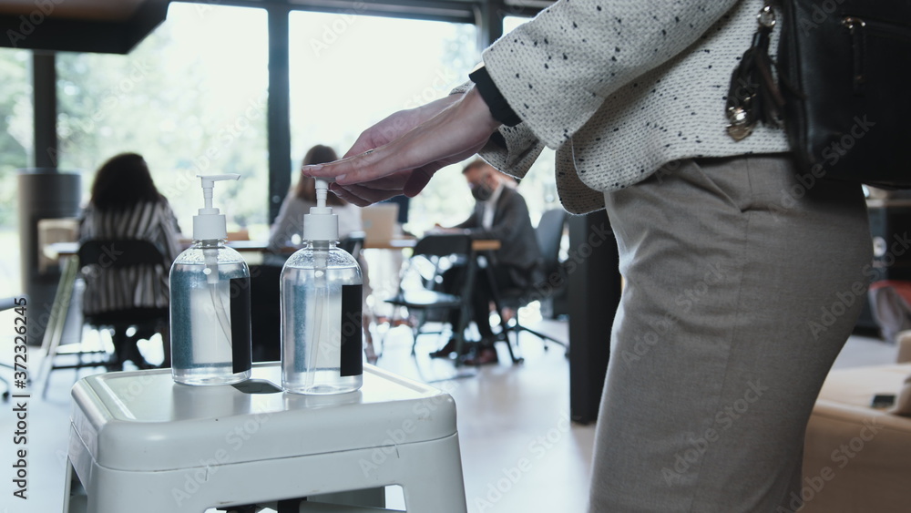 Hand sanitizer station at office workplace. Close-up diverse business people disinfect hands coming to work slow motion. Hand sanitizer station at office workplace. Close-up diverse business people disinfect hands coming to work slow motion.