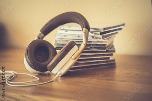 Stereo headphone and compact discs on wooden background photo