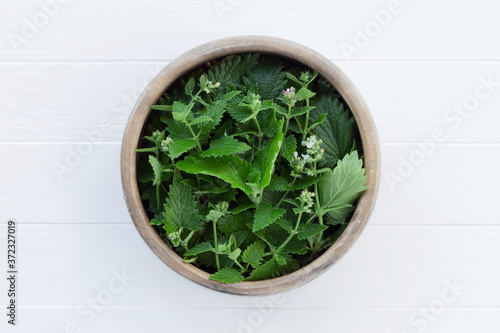 Fresh lemon balm leaves, melissa in a wooden bowl.  Fresh organic herbs, top view. Fragrant seasoning. Cuisine ingredient, condiment.