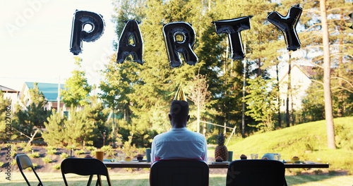 Slika na platnu Rear view sad lonely African young man sitting alone celebrating birthday party at home on self isolation slow motion