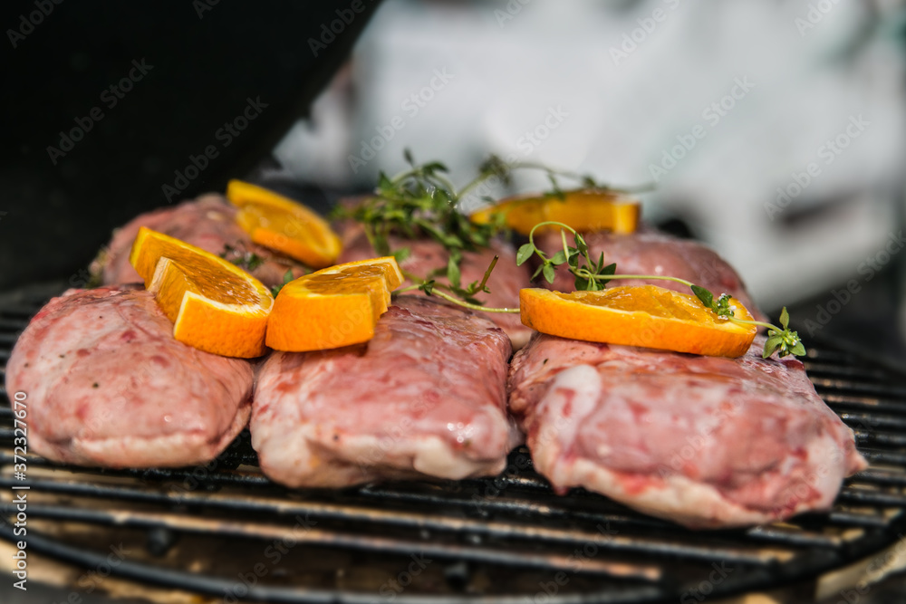 Pork meat with orange slices, prepared on grill. Closeup