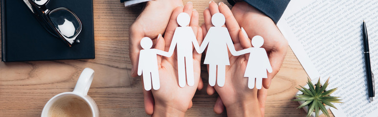 panoramic crop of lawyer and woman holding paper cut family near cup, insurance agreement, notebook and plant