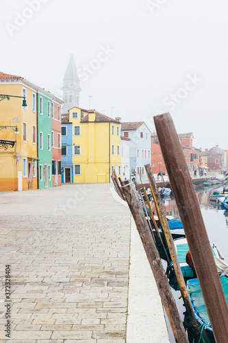 Island of Burano, Venice, Italy. Nice street with colorful houses and boats. Tourist place, postcard of Venice. Foggy day. © A.J. Pedrosa