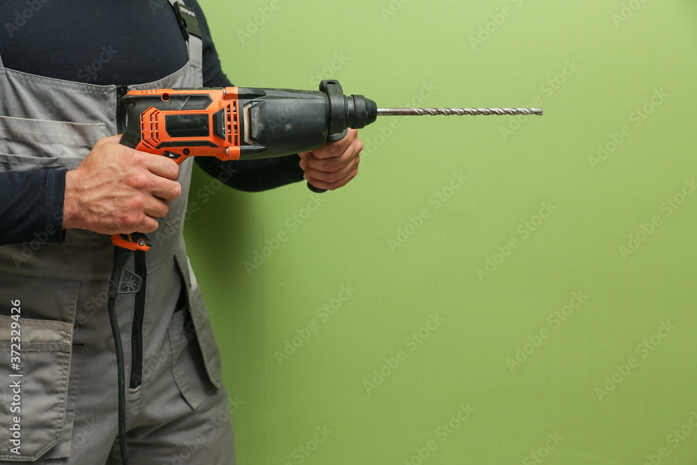 the hands of the builder are holding an hammer drill the hands of the builder are holding an hammer drill
