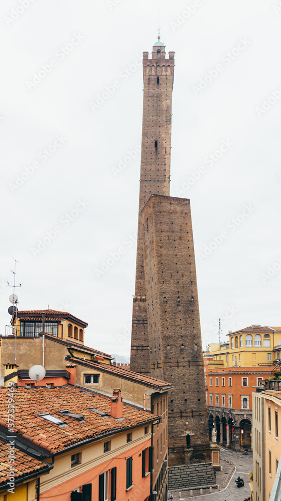 Two famous falling towers Asinelli and Garisenda in the night, Bologna, Emilia-Romagna, Italy. Vertical panoramic.