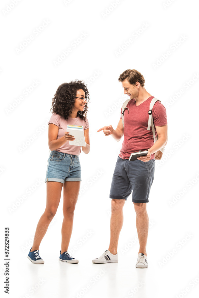 Student pointing with finger at book near african american friend on white background Student pointing with finger at book near african american friend on white background