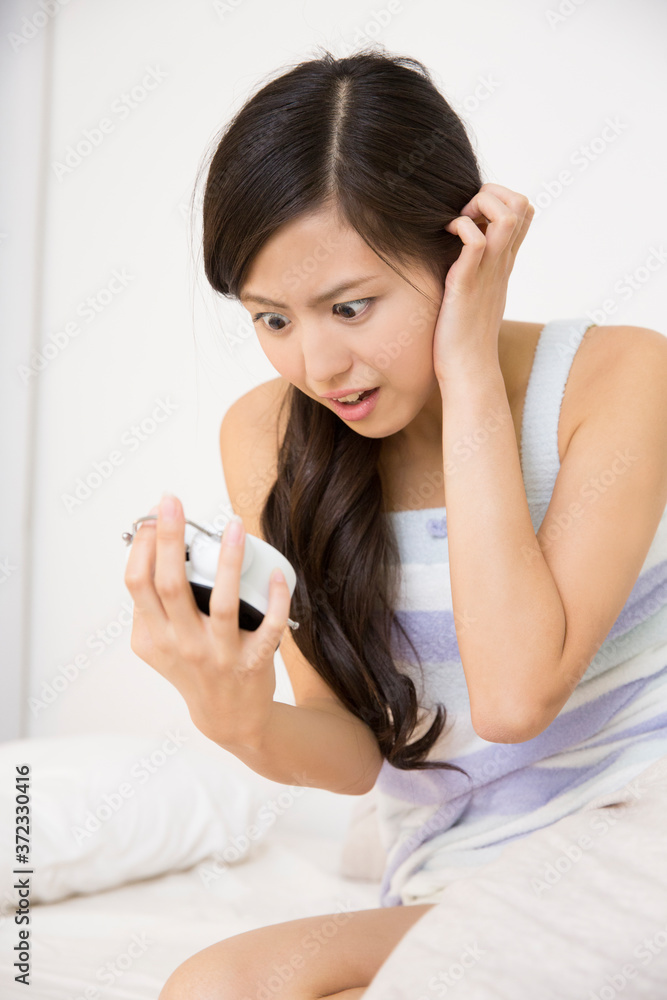 目覚まし時計を見る女性 目覚まし時計を見る女性