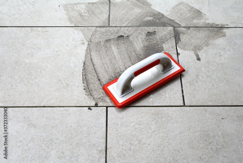 Grouting ceramic tiles. Filling the space between tiles using a rubber trowel. photo