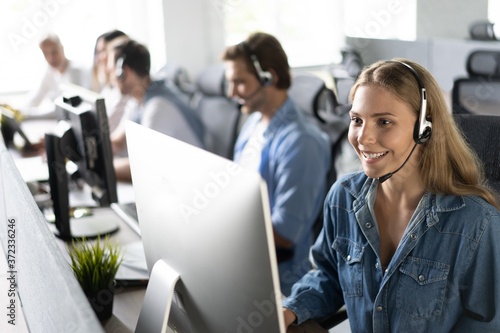 Fotografiet How can I help you? Beautiful call center workers in headphones are working at modern office