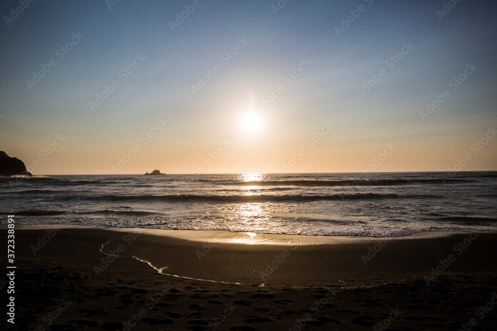 Obraz premium Beautiful sunset with splashing waves on the beach of False Klamath Cove in Redwood National Park (California).