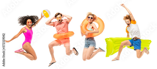 Panoramic shot of multicultural friends with inflatable mattress and ball jumping isolated on white