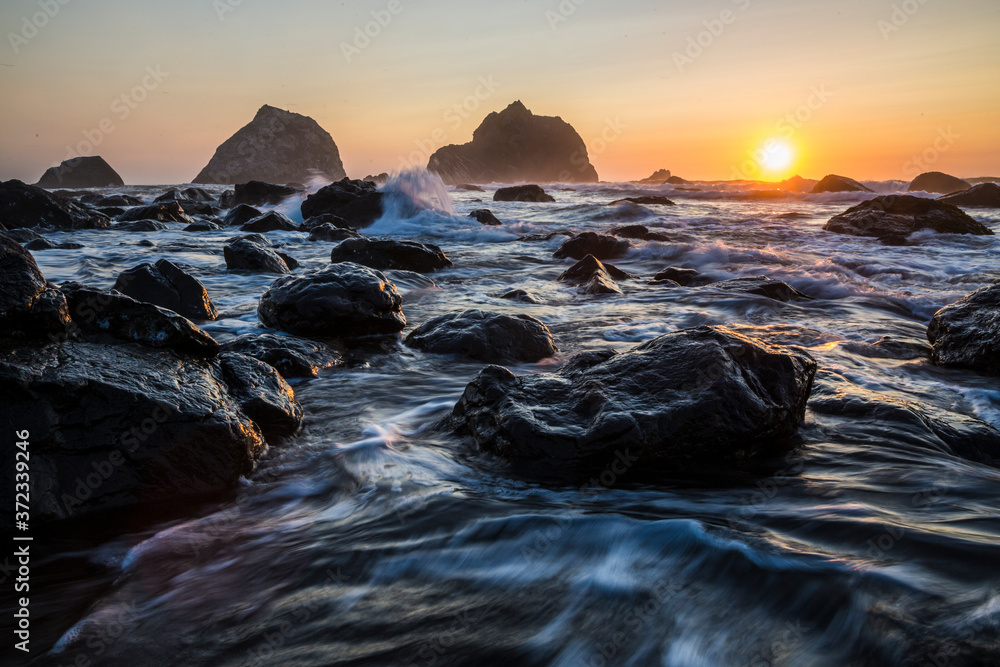 Obraz premium Beautiful sunset with splashing waves on the beach of False Klamath Cove in Redwood National Park (California).