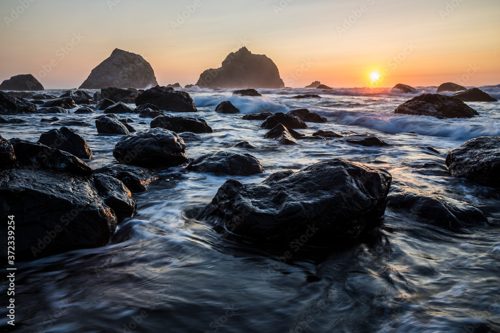 Obraz premium Beautiful sunset with splashing waves on the beach of False Klamath Cove in Redwood National Park (California).