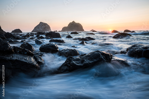 Beautiful sunset with splashing waves on the beach of False Klamath Cove in Redwood National Park (California).