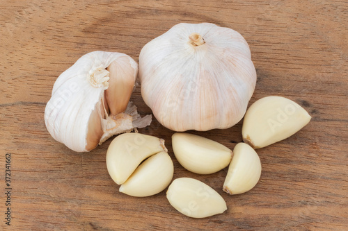 Two young garlic heads and cloves over wood table
