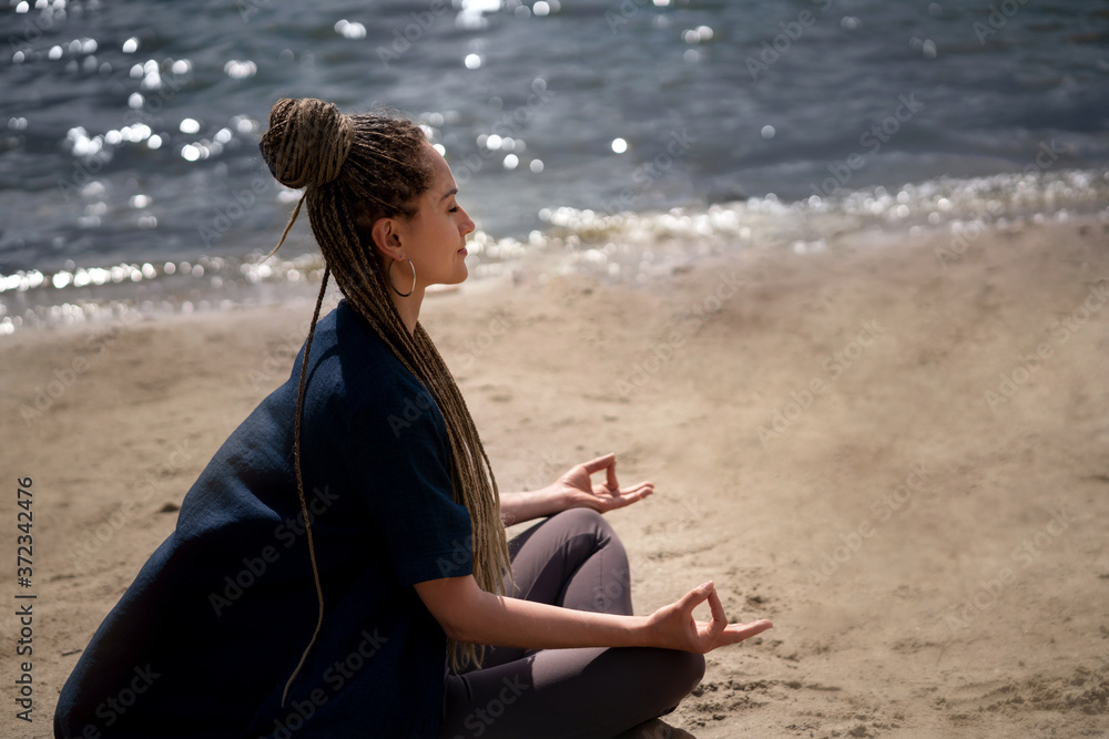 Woman doing yoga asana on the beach with closed eyes.