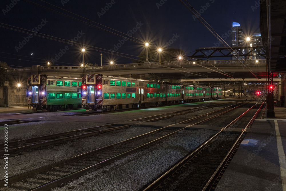 Green windows of resting commuter trains in urban Chicago at night