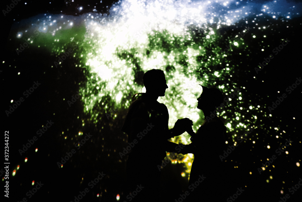 Couple dancing together in dark room with projection of starry sky Couple dancing together in dark room with projection of starry sky