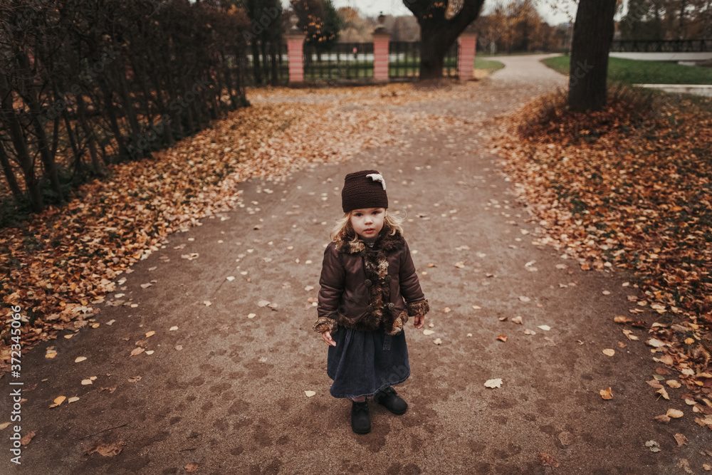 Little girl standing on the road with autumn leaves Little girl standing on the road with autumn leaves
