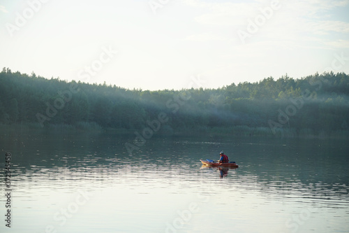The guy floats on a canoe on the lake in the fog
