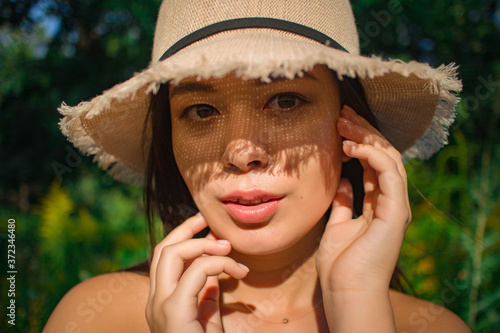 young brunette in a straw hat outdoors close up
