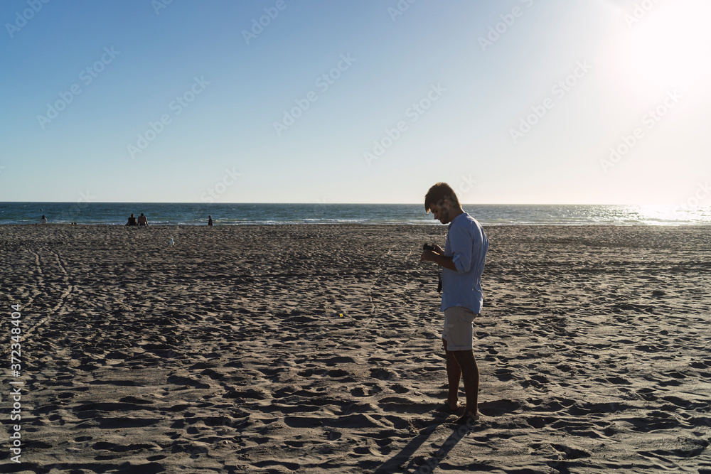 Chico joven mirando una camara fotografica en la playa Chico joven mirando una camara fotografica en la playa