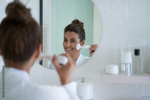 Happy woman enjoying morning procedures in the bathroom