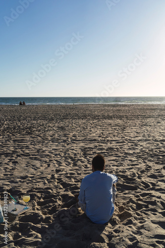 Chico joven vestido de camisa sentado en la playa © MiguelAngelJunquera