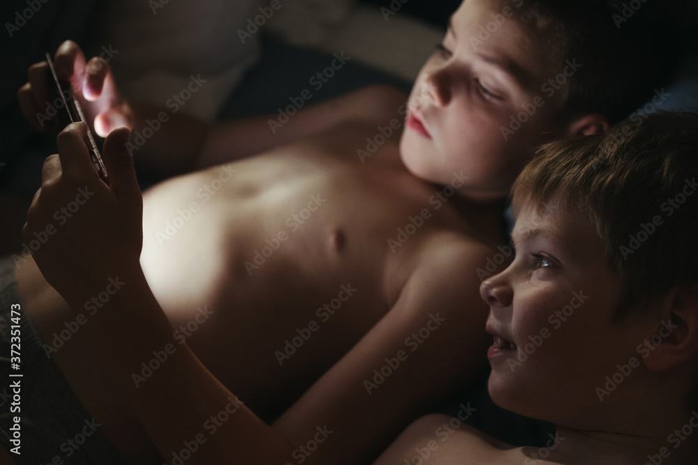 Kids enjoying reading ebook in cozy bedroom. Kids enjoying reading ebook in cozy bedroom.