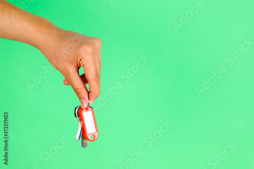 House key in woman hand. green background