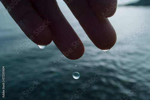 water drop falling from fingers into the sea photo